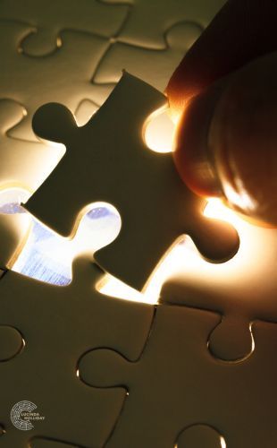 Hand placing last piece of jigsaw in place Hand placing last piece of jigsaw in place