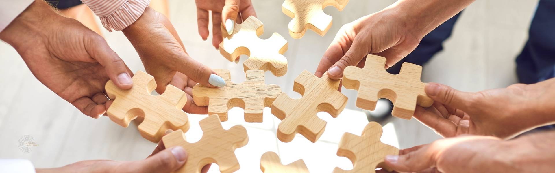 Many hands holding pieces of a jigsaw